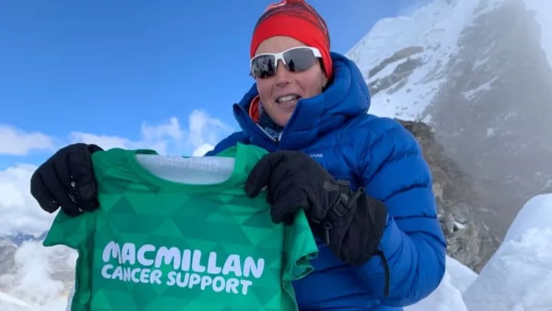 Shuanna Burke poses with a cancer research T-shirt for her GoFundMe after summiting Mount Everest in 2026.
