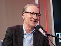 Bill Maher sitting in front of a microphone