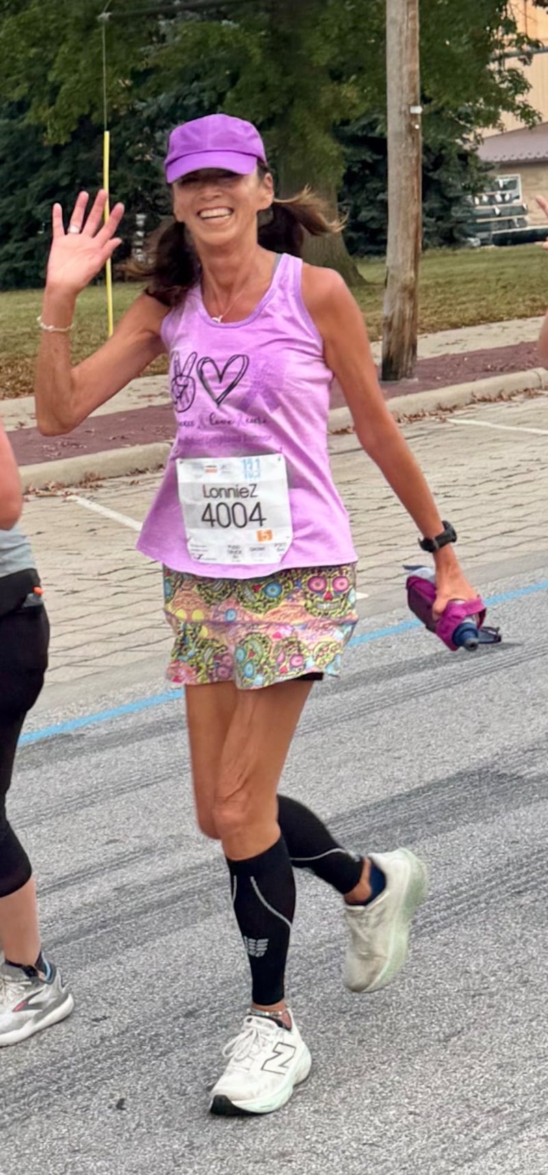 63-year-old Lonnie Zofchak is pictured waving as she runs in a race.