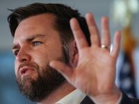 J.D. Vance holds up a hand while speaking at an event.