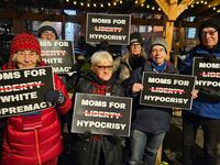 A group of protesters hold signs at a Moms for Liberty event