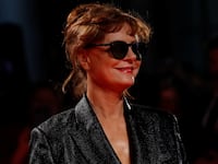 Susan Sarandon, wearing a black dress and glasses, smiles at a film festival.