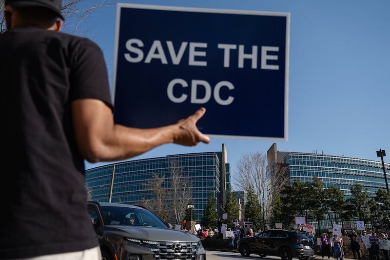 ATLANTA, GEORGIA - MARCH 12: People protesting personnel cuts at the Centers for Disease Control (CDC) hold signs outside the organization's main headquarters on March 12, 2025 in Atlanta, Georgia. Some Centers for Disease Control and Prevention (CDC) employees have sent a letter to CDC leadership, they argue their dismissals were unfair and violated due process as they face a deadline that could officially end their employment status. (Photo by Elijah Nouvelage/Getty Images)