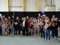 DULLES, VIRGINIA - MAY 12: Newly arrived South Africans wait to hear welcome statements from U.S. government officials in a hangar at Atlantic Aviation Dulles near Washington Dulles International Airport on May 12, 2025 in Dulles, Virginia. Dozens of white South Africans, also called Afrikaners, accepted an invitation from the Trump Administration to come to the United States as refugees. They say they are fleeing job discrimination and racial violence in their home country. Trump has halted virtually all refugee admissions for people fleeing famine and war but has created an expedited path into the U.S. for Afrikaners, descendants of white Europeans who created and led the brutal apartheid regime in South Africa from 1948 to 1994. (Photo by Chip Somodevilla/Getty Images)