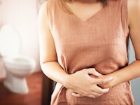 woman clutching stomach in front of toilet american gut project poop crap shit bateria microbiome
