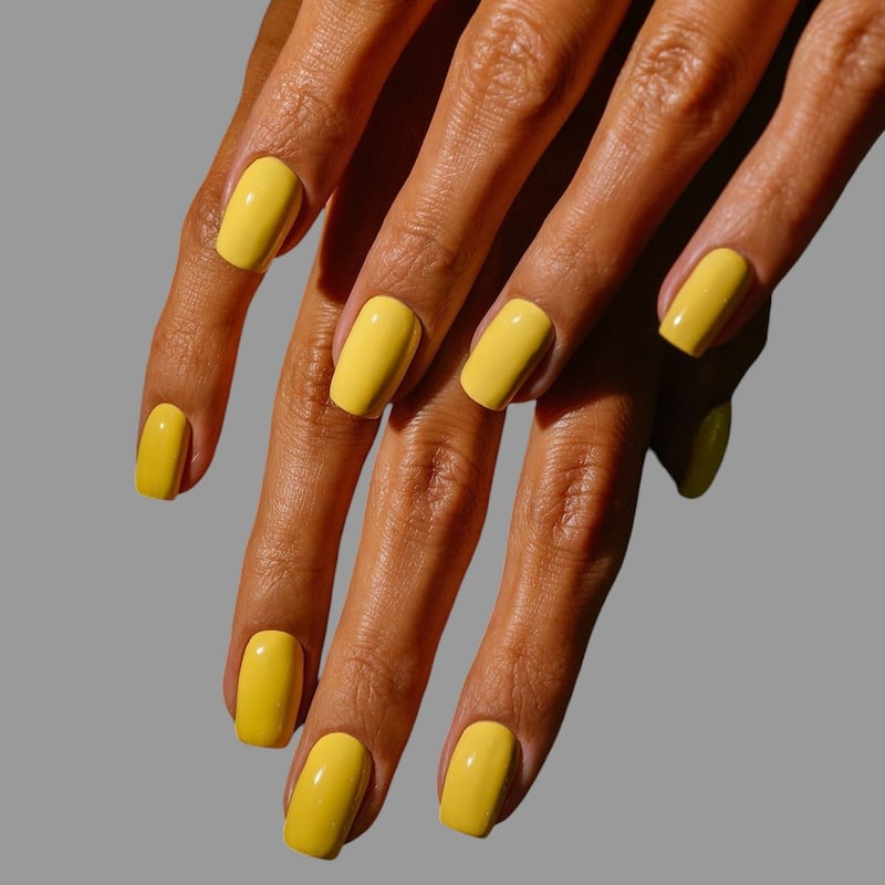 Young woman's hands with colorful and decorated nail manicure with modern, innovative and elegant shapes and drawings and gray background