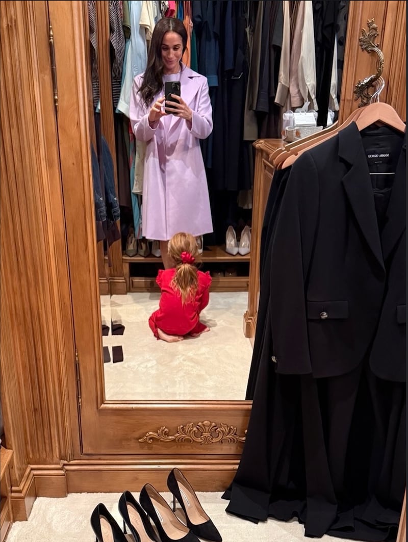 Meghan Markle and her daughter, Princess Lilibet, pose for a mirror selfie, showcasing Lilibet’s all-red outfit and matching red hair.