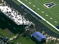 Students and staff gather next to the football field after law enforcement officers responded to a fatal shooting at Apalachee High School.