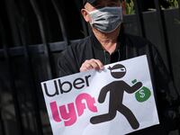 A person holds a placard criticizing Uber and Lyft.