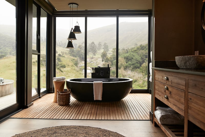 Pendant light hanging over bathtub in bathroom with large window of luxury rental vacation villa