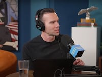 Pod Save America host Jon Favreau speaks into a microphone.