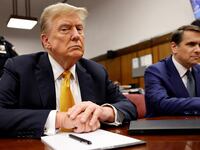 Donald Trump frowns at the camera, wearing a suit, while sitting in a courtroom at Manhattan Criminal Court with his attorney Todd Blanche.