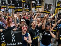 Members of the Writers Guild of America East and SAG-AFTRA cheer and react as they walk the picket line outside Netflix.