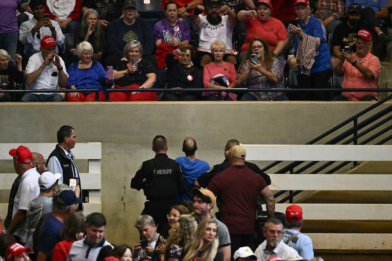 A protestor is escorted out by security as President Donald Trump speaks during a campaign rally at T. Ed Garrison Arena in Pendleton, South Carolina on October 21, 2026.