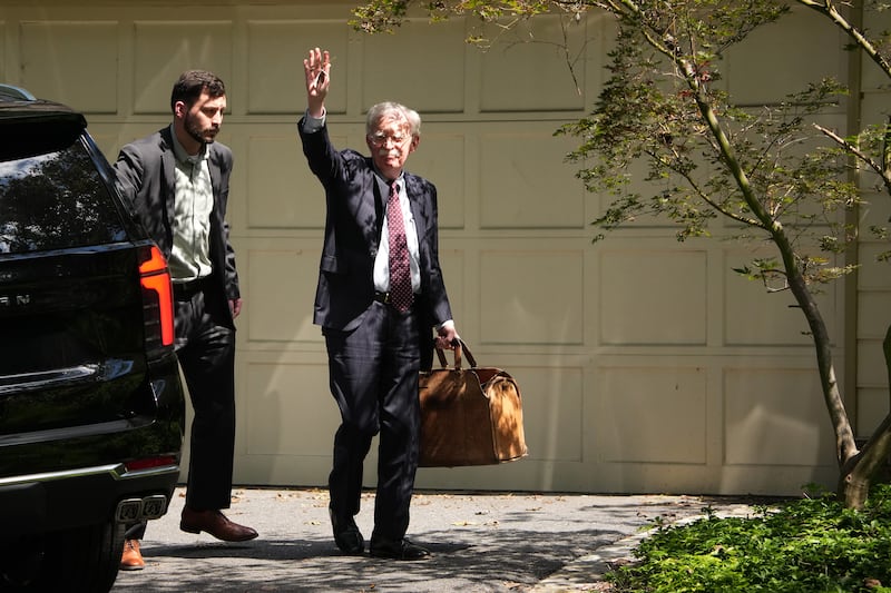 John Bolton, waves as he arrives home, as the FBI searches his house August 22, 2025 in Bethesda, Maryland.