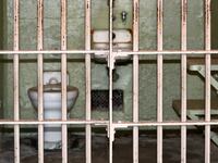 A picture of a jail cell, as seen through the bars.
