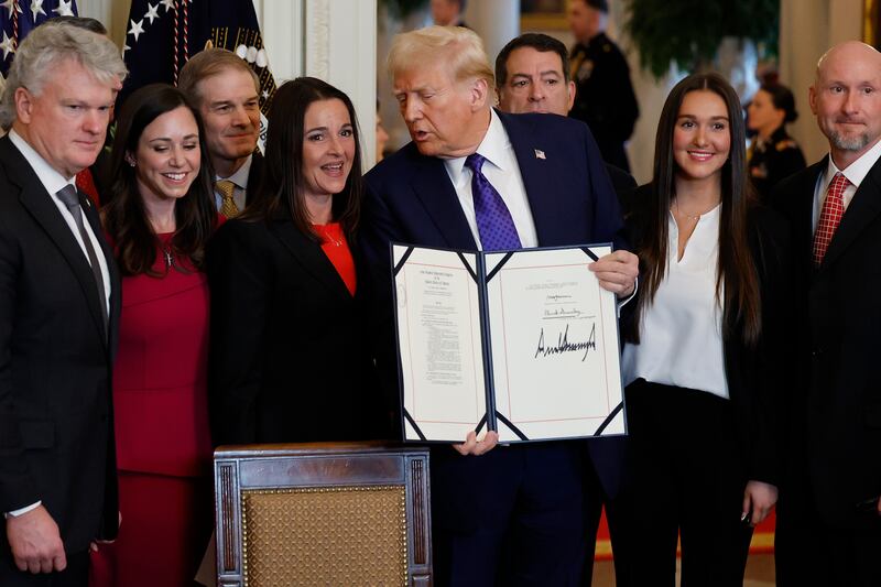 WASHINGTON, DC - JANUARY 29: Surrounded by members of Congress and the family of Laken Riley, U.S. President Donald Trump poses with the signed Laken Riley Act, the first piece of legislation passed during his second term in office, in the East Room of the White House on January 29, 2025 in Washington, DC. Jason Riley and Allyson Philips, the parents of 22-year-old Laken Riley, a University of Georgia nursing student who was murdered in 2024 by an undocumented immigrant, attended the signing ceremony. Among other measures, the law directs law enforcement authorities to detain and deport immigrants who are accused but not yet convicted of specific crimes, if they are in the country illegally. (Photo by Chip Somodevilla/Getty Images)