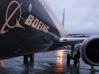 A Boeing jet sits on a runway with a cloudy sky in the background.