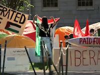 A protester hangs a Palestinian flag at an encampment on Harvard Yard.