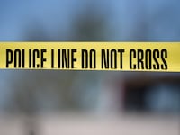 Tape saying "POLICE LINE DO NOT CROSS" in front of a sunny, blurred background