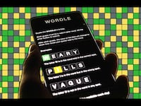 A photo illustration of a person holding a phone playing Wordle.