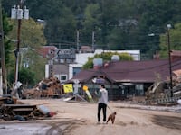 A woman walks her dog on a destroyed street in Asheville, North Carolina.