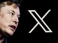 Elon Musk's photo is displayed on a phone screen in front of a computer screen displaying the new logo of 'Twitter' i