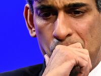 Rishi Sunak puts his hand to his mouth on stage at an event.