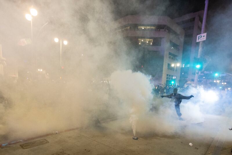 A smoke bomb fill the air as police clash with protesters during a demonstration following federal immigration operations in Los Angeles on June 9, 2025.
