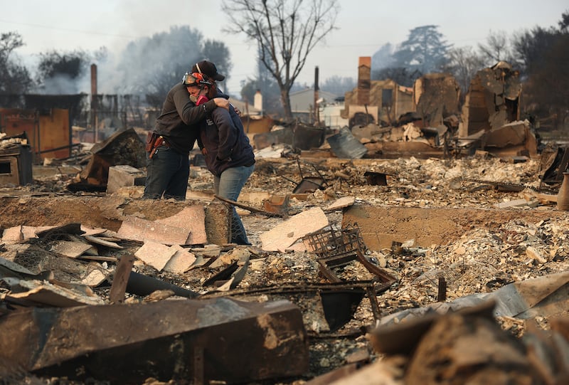 Khaled Fouad (L) and Mimi Laine (R) embrace as they inspect a family member's property that was destroyed by Eaton Fire on Jan. 9, 2025 in Altadena, California.