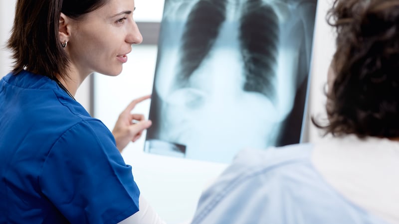 In a hospital, a female doctor is discussing and explaining the results of a chest X-ray to an elderly female patient, a process that showcases medical diagnosis.