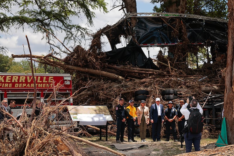 President Donald Trump and First Lady Melania pose for pictures with local emergency services personnel on July 11 in front of a mobile concert stage in Louise Hays Park that was destroyed during flash flooding along the Guadalupe River in Kerrville, Texas.