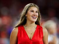Ava Hunt smiles while walking on an NFL field in a red top.