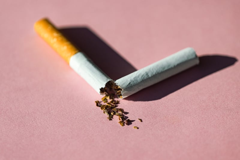 A broken cigarette over a pink background