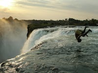 A Zambian man jumps into a pool on the edge of Victoria Falls