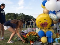 Two students place flowers at a memorial outside of Apalachee High School