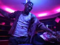 A still of Nassim Lyes punches a man on a table in 'Mayhem!”