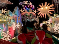 Guests take a boat ride through \"It's a Small World\" ride decorated for the holiday season during the Star Wars Season of The Force at Disneyland