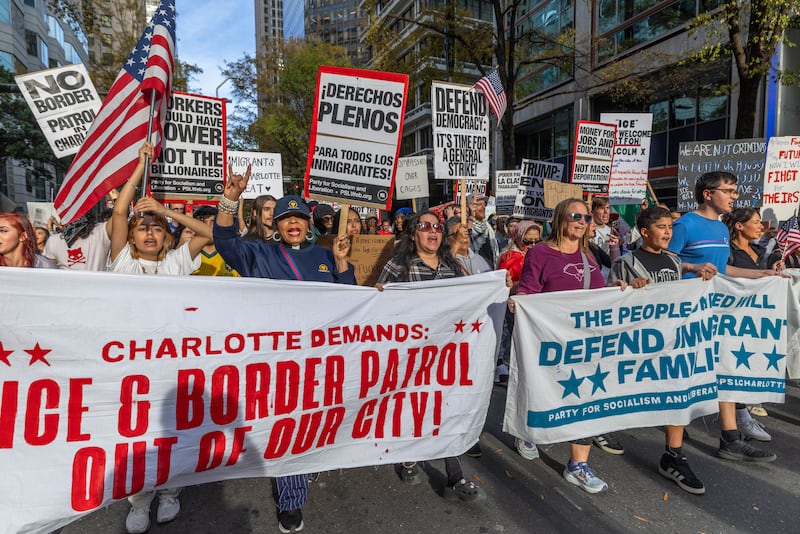 Protesters march through uptown after gathering at First Ward Park for the "No Border Patrol In Charlotte" rally