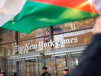 A Palestinian flag being waved in front of New York Times building.