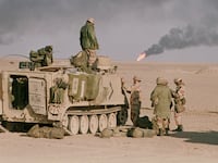 A U.S. armored personnel carrier sits in the desert at the end of the Gulf War. Oil wells burn in the background. (Photo by Peter Turnley/Corbis/VCG via Getty Images)