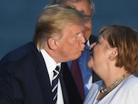 Donald Trump kisses German Chancellor Angela Merkel during a family photo opportunity at the G7 summit in Biarritz, France, Aug. 25, 2019.