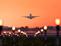 Stock image of an airplane taking off at sunrise.