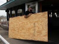 A man carries plywood into a store ahead of the arrival of Hurricane Idalia in Cedar Key, Florida.