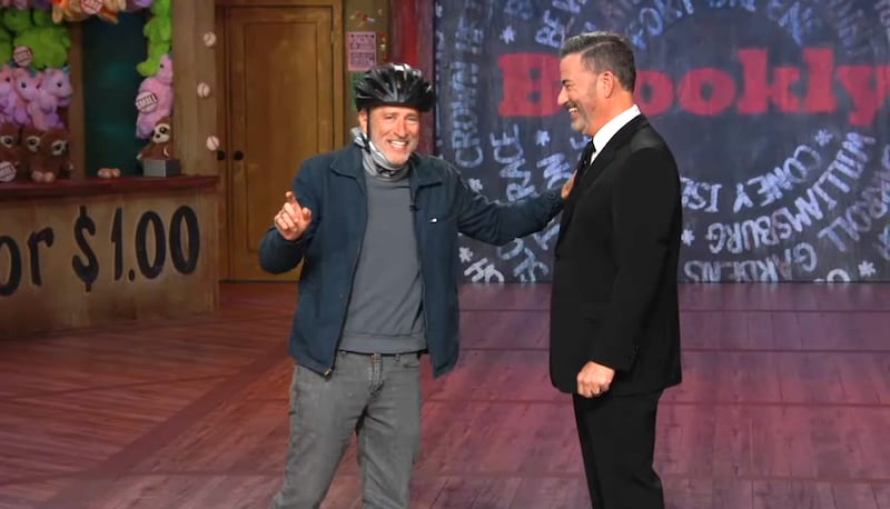 The Daily Show, Jon Stewart with a helmet laughing with Jimmy Kimmel.