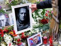 A woman places a portrait of late Russian opposition leader Alexei Navalny on his memorial.