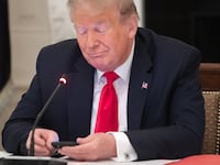Donald Trump uses his cellphone as he holds a roundtable discussion in the State Dining Room of the White House in Washington, DC, June 18, 2020