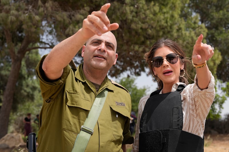 Kristi Noem and an Israeli army officer point toward the Gaza Strip while visiting the Black Arrow memorial site in the Kibbutz Mefalsim.