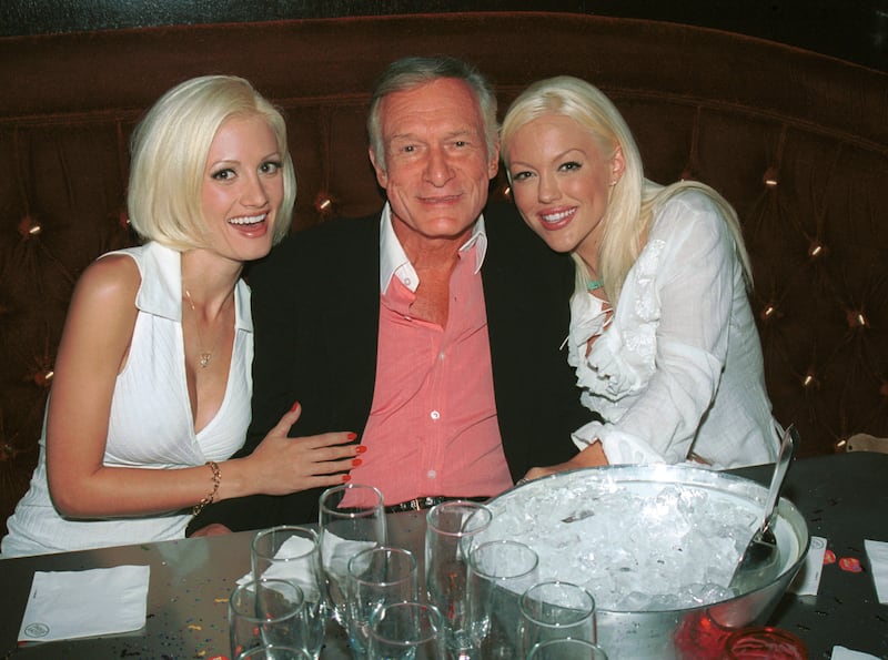 Models Holly Madison and Tiffany Holiday hug Playboy founder Hugh Hefner (center) during a birthday dinner party for Hef's two other girlfriends, Bridget Marquardt and Izabella Kasprzyk, in Beverly Hills, California, on September 12, 2002 in Beverly Hills, California.