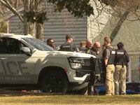 Police are seen outside an apartment that was searched in connection with the killing of a 22-year-old nursing student.